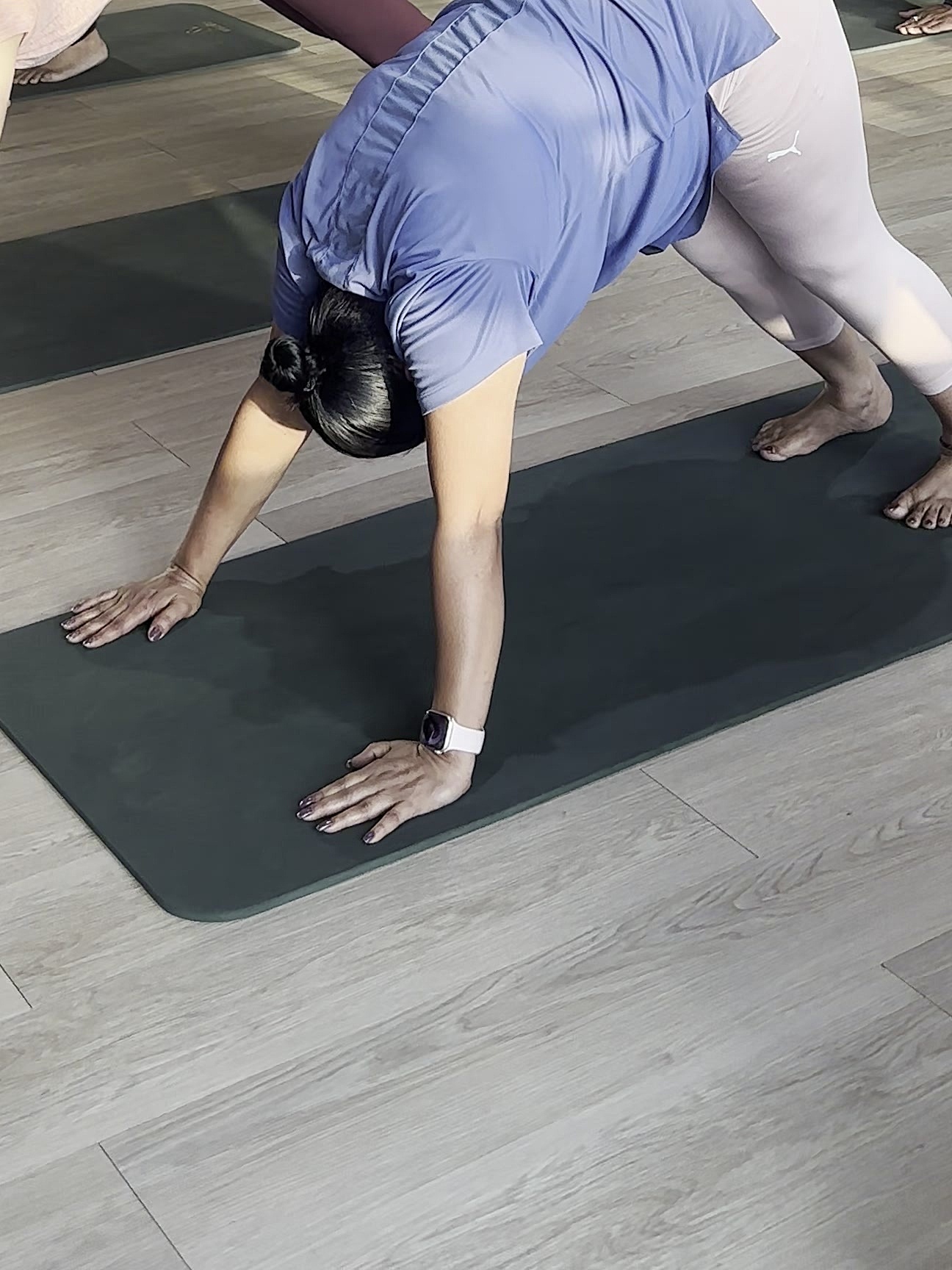 A student in a wide-legged forward fold, hands planted on the mat